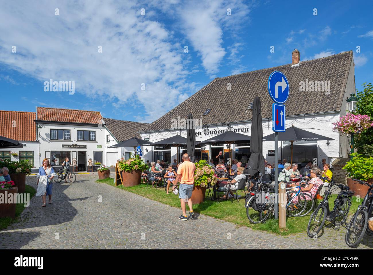 Touristen im Straßencafé des Pubs den Ouden Toren auf dem Marktplatz im Dorf Lissewege bei Brügge im Sommer, Westflandern, Belgien Stockfoto