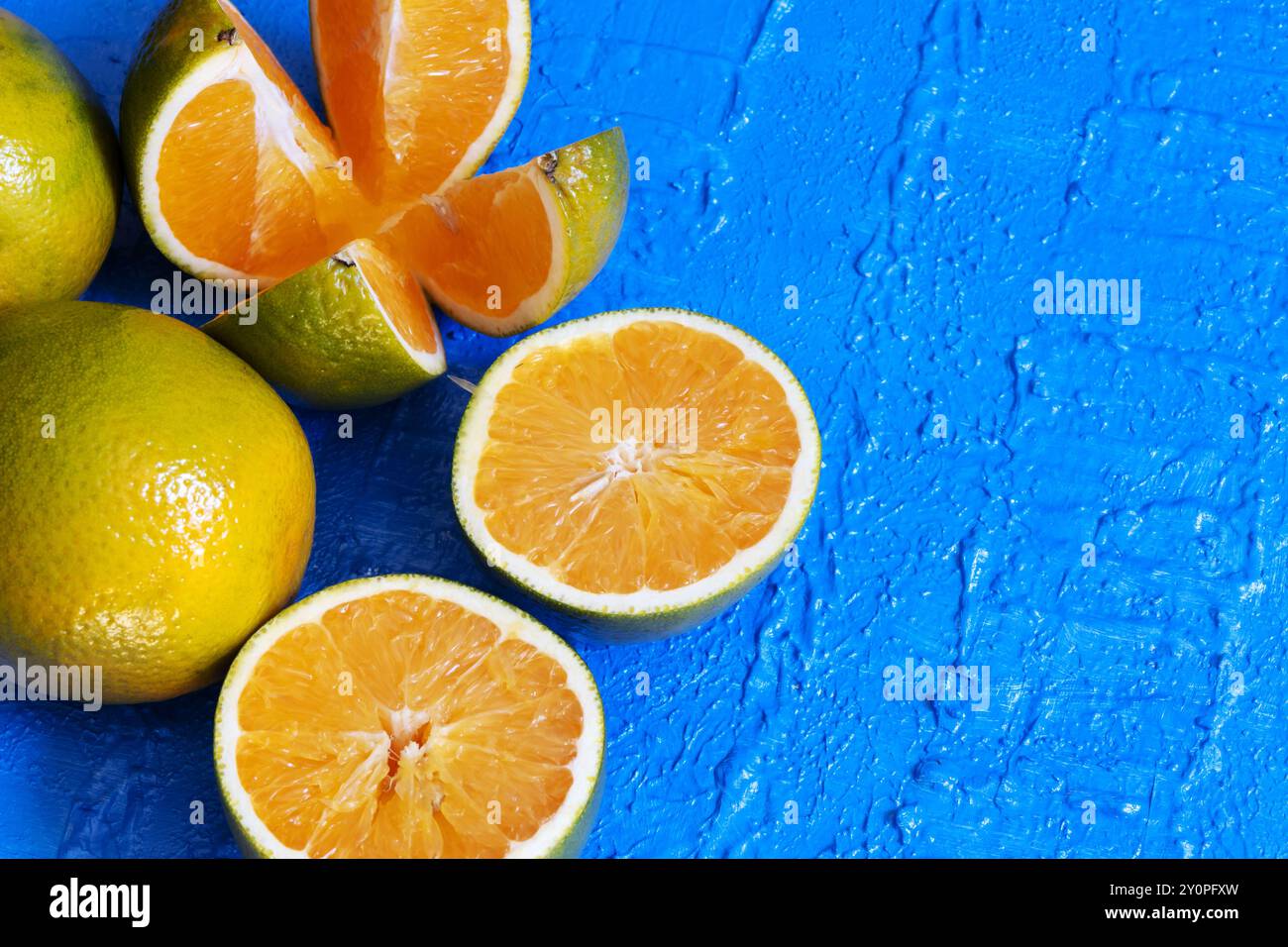 Eine in Viertel geschnittene Orange neben einer halben Orange und einer ganzen Orange. Stockfoto