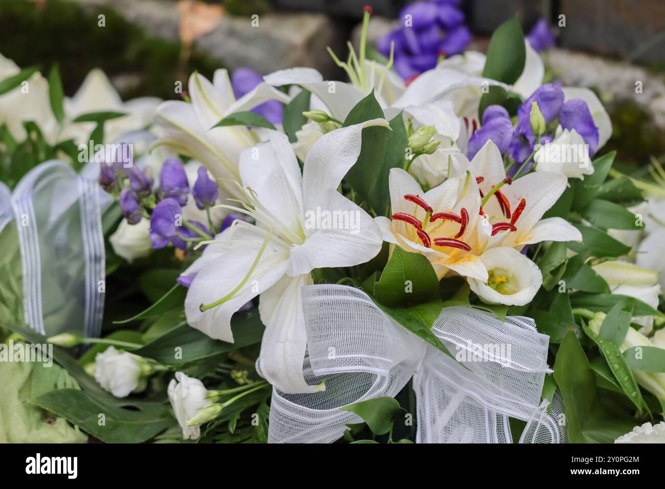 Schöne Grabblumen auf dem Friedhof. Verwandte wollen sich mit Blumen an die Verstorbenen erinnern. Ein wunderschöner Blumenstrauß tröstet trauernde Verwandte. Stockfoto