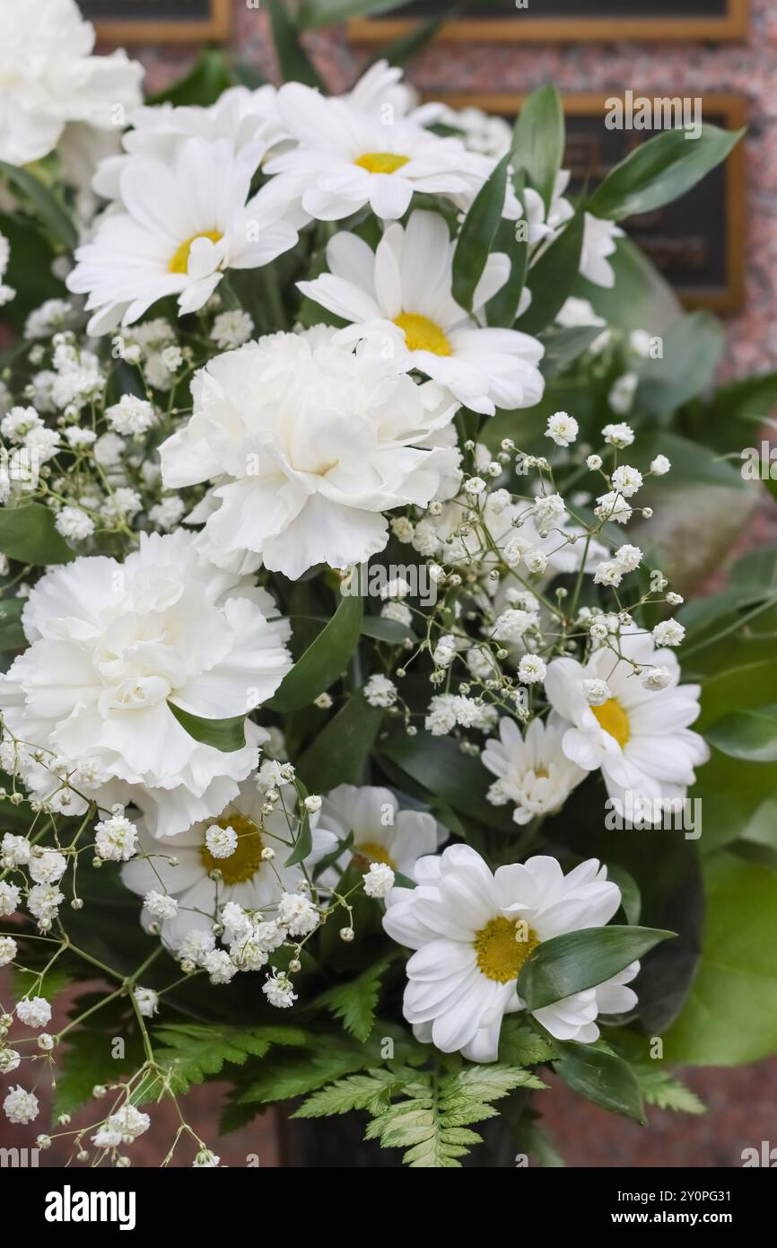 Schöne Grabblumen auf dem Friedhof. Verwandte wollen sich mit Blumen an die Verstorbenen erinnern. Ein wunderschöner Blumenstrauß tröstet trauernde Verwandte. Stockfoto