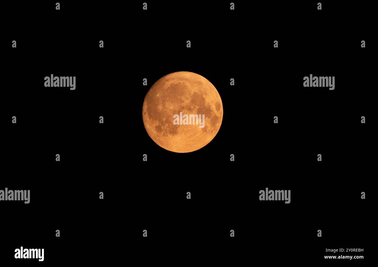 Blue Super Moon Looking Orange, August 2024. Rauchpartikel ließen das Licht in der Atmosphäre orange und rot erscheinen. Das schuf einen trüben Himmel und einen vollen Stockfoto