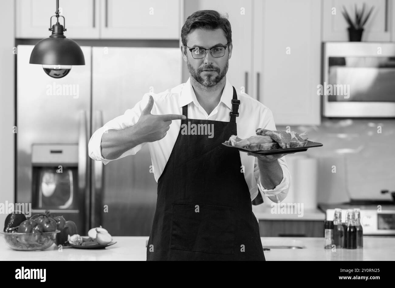 Rindfleisch-Steak-Konzept. Mann mittleren Alters, der Fleisch kocht, Rindfleisch Steak in der Küche. Mann in der Küche mit Fleisch und rohem Rindfleisch. Stockfoto