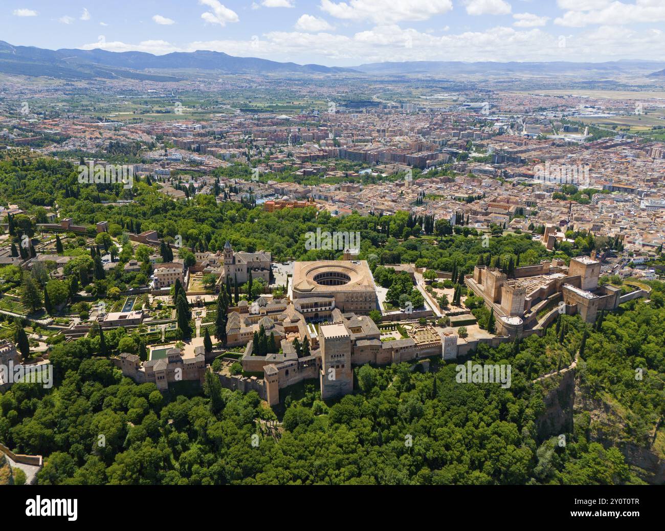 Blick aus der Vogelperspektive auf eine Burganlage umgeben von grünen Bäumen und Hügeln mit einer Stadt im Hintergrund, Blick aus der Vogelperspektive, Alhambra, Andalusien, Granada, Spanien, E Stockfoto