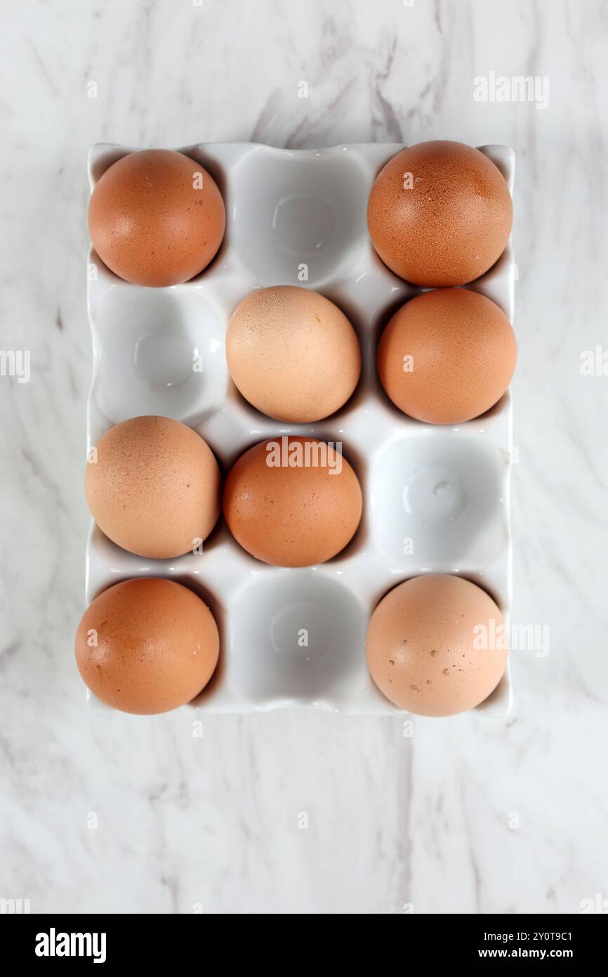 Eier von oben auf Keramikeimer, isoliert auf weißem Marmortisch Stockfoto