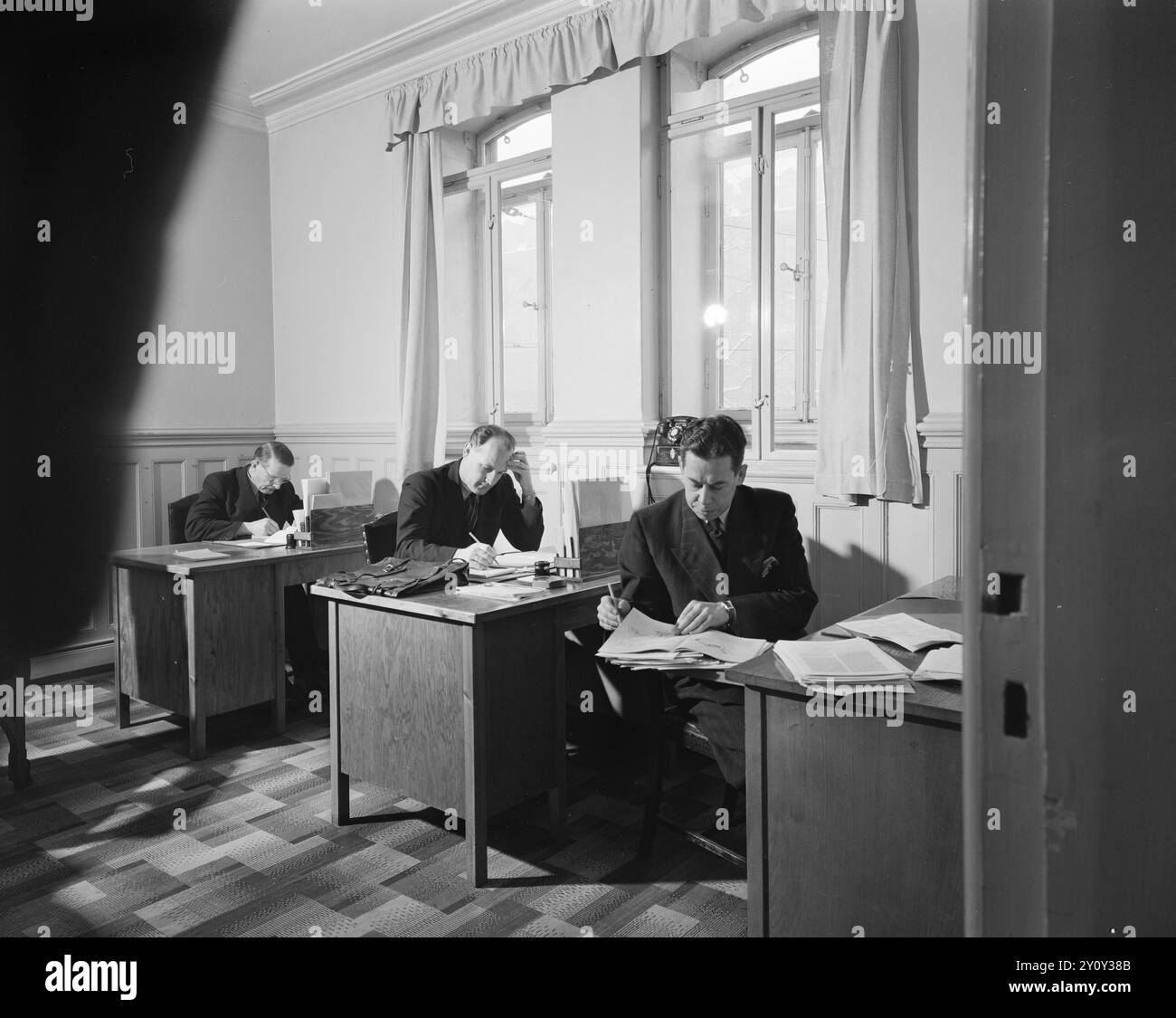 Tatsächlich 1951: Das ist der Storting unwürdig. Arbeitsbedingungen am Storting. Im Justizausschuss gibt es "nur" 10 Personen, verteilt auf den zweigeteilten Raum. Im Fenster befindet sich das einzige Telefon der Website, es gibt 4 Schreibtische und einen Schreibmaschinentisch - wo die einzige Schreibmaschine nicht einmal angekettet ist. Wie Sie sehen, gibt es keinen Hinweis auf Schreibtischlampen, obwohl sie mehrere Meter vom nächsten der beiden dem Ausschuss zugewiesenen Lampenpunkte entfernt sind. Dennoch haben die Abgeordneten Martin Smeby, Leif Granli und Reidar Strømdal einige der Arbeiten des Tages erledigt. Fuß: Aktuell / NTB ***P Stockfoto