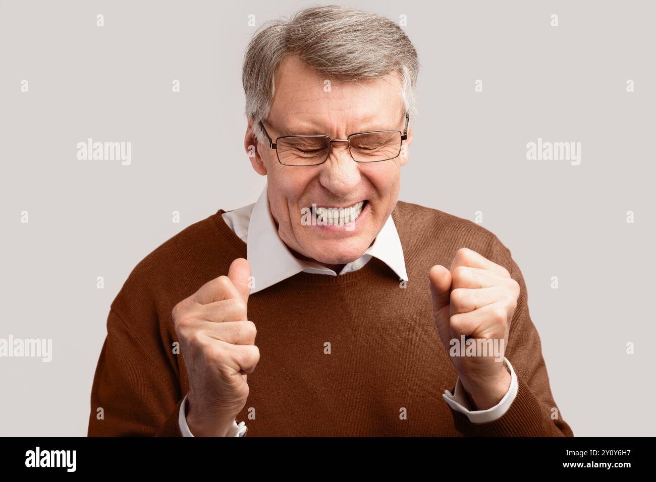 Angry Elderly Man Fäuste Klammernden Posing Auf Grauem Hintergrund, Studio Stockfoto