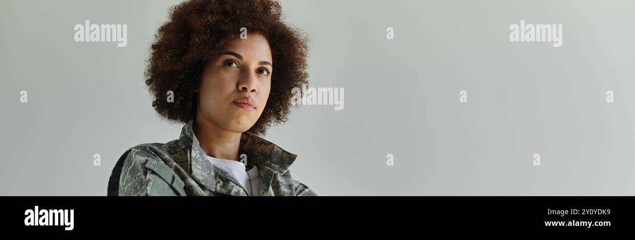 Eine entschlossene junge afroamerikanische Frau verkörpert Stärke, während sie eine Tarnuniform trägt. Stockfoto