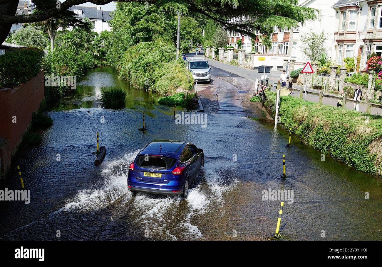 A Car Creating A Splash überquert die Ford über den Sid River, Sidmouth, Großbritannien Stockfoto