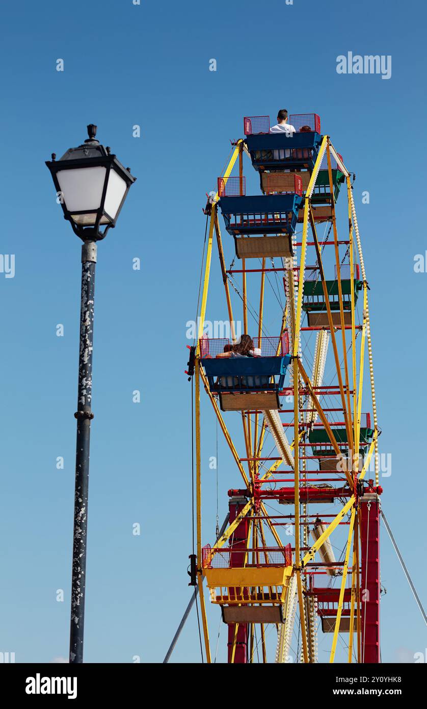 Menschen, Familien, die Auf Einem Vintage Iron and Steel Ferris Wheel auf Einem Messegelände in Mudeford, Großbritannien, fahren Stockfoto