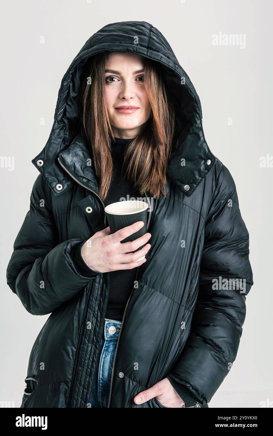 Porträt einer Frau mit Kapuzenmantel, die eine Tasse Kaffee hält Stockfoto