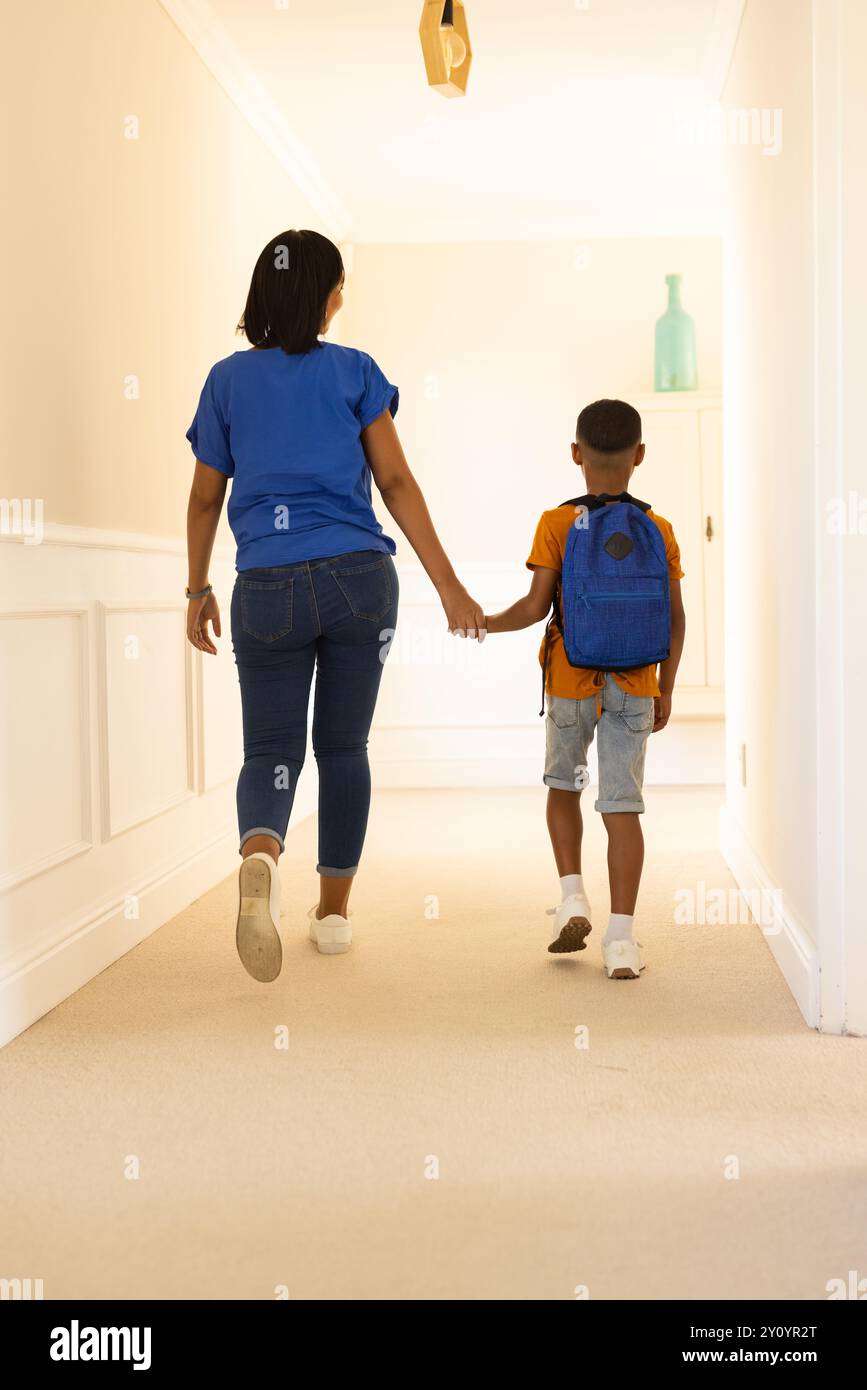 Ich gehe den Flur entlang, Mutter hält die Hand des Sohnes, Junge im Rucksack Stockfoto