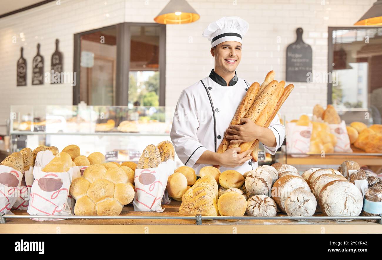 Junger männlicher Bäcker, der Baguettes in einer Bäckerei hält Stockfoto