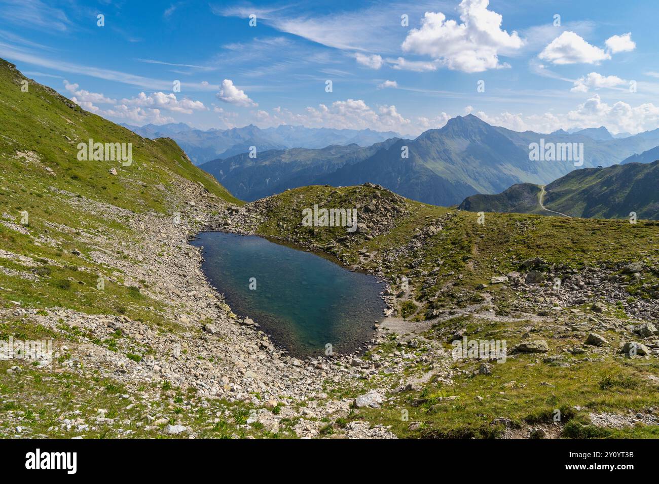 Kleiner See in den Vorarlberger Bergen, Panorama mit steilen Bergen und Almwiesen, Geröllfelder und Felswände, Sommer in den alpen, Urlaub Stockfoto