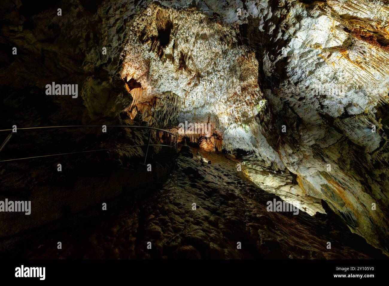 In der Freiheitshöhle von Demänovská, Slowakei – beleuchtete Felsformationen und ein gewundener Pfad schaffen eine geheimnisvolle unterirdische Atmosphäre. Stockfoto