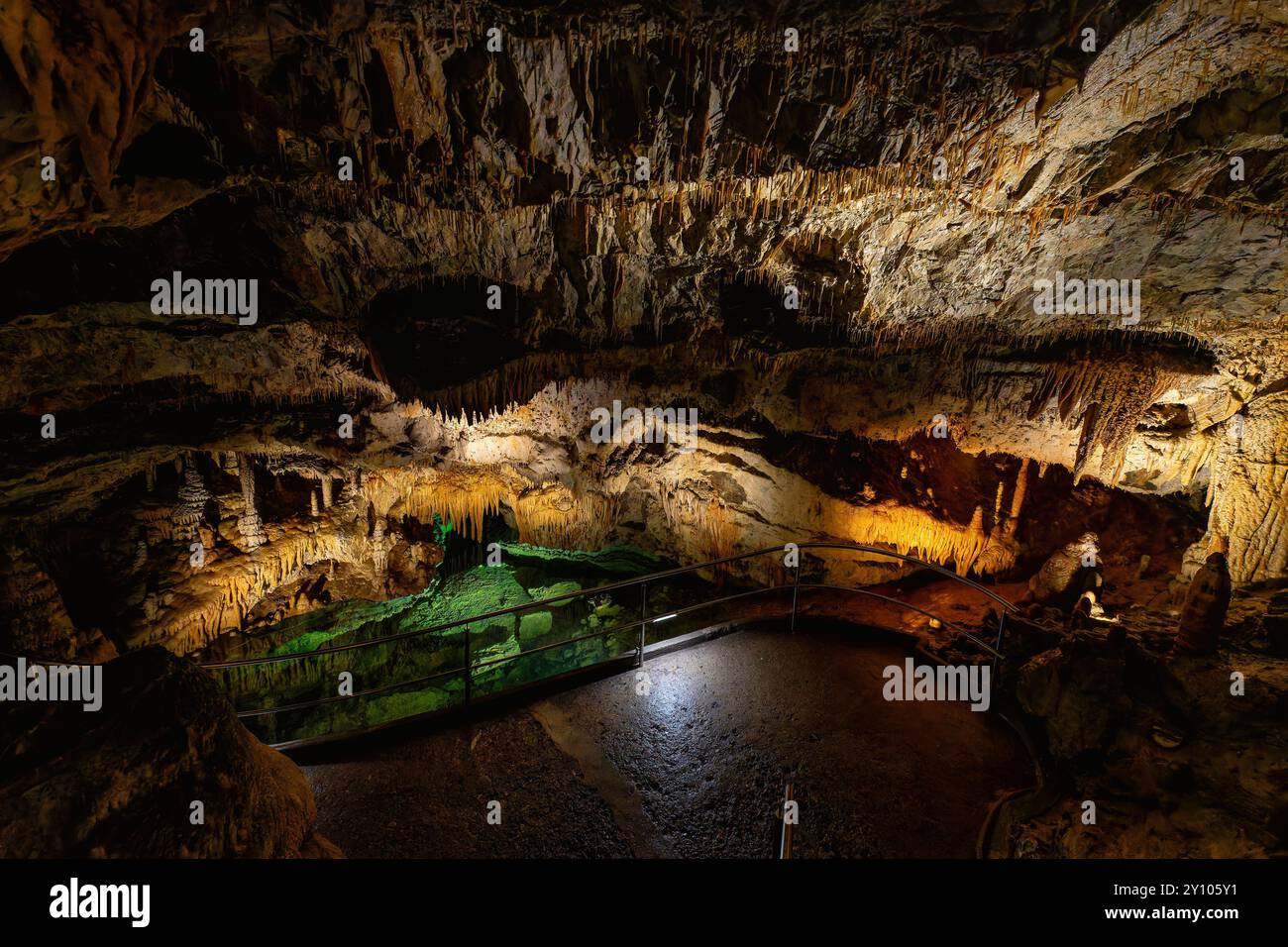 Magische unterirdische Welt in der Freiheitshöhle von Demänovská, Slowakei, mit beleuchteten Felsformationen, Stalaktiten und einem grün beleuchteten Höhlenpool. Stockfoto