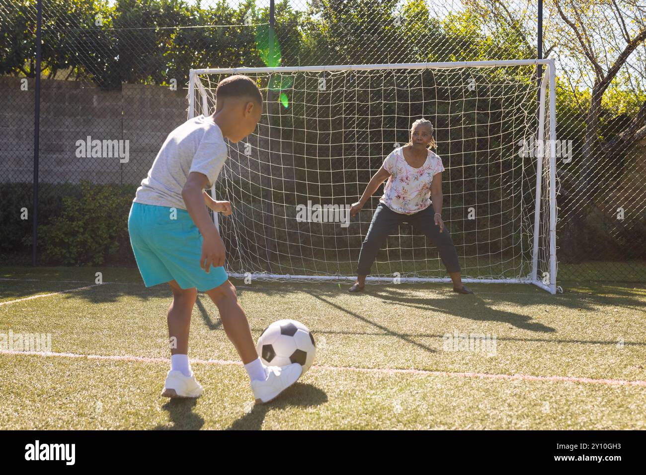 Fußball spielen, Junge tritt als Torhüter auf dem Feld auf die Frau Stockfoto