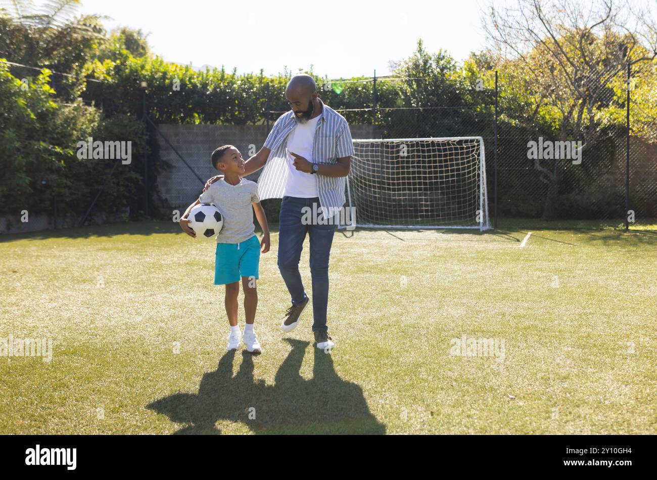 Fußball spielen, Großvater und Enkel gehen mit Ball auf dem Spielfeld, arbeiten im Freien, Kopierraum Stockfoto
