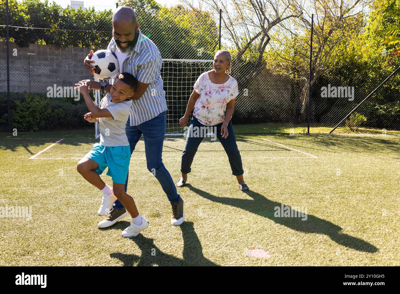 Großeltern und Enkel genießen Outdoor-Aktivitäten und spielen Fußball im Hinterhof Stockfoto