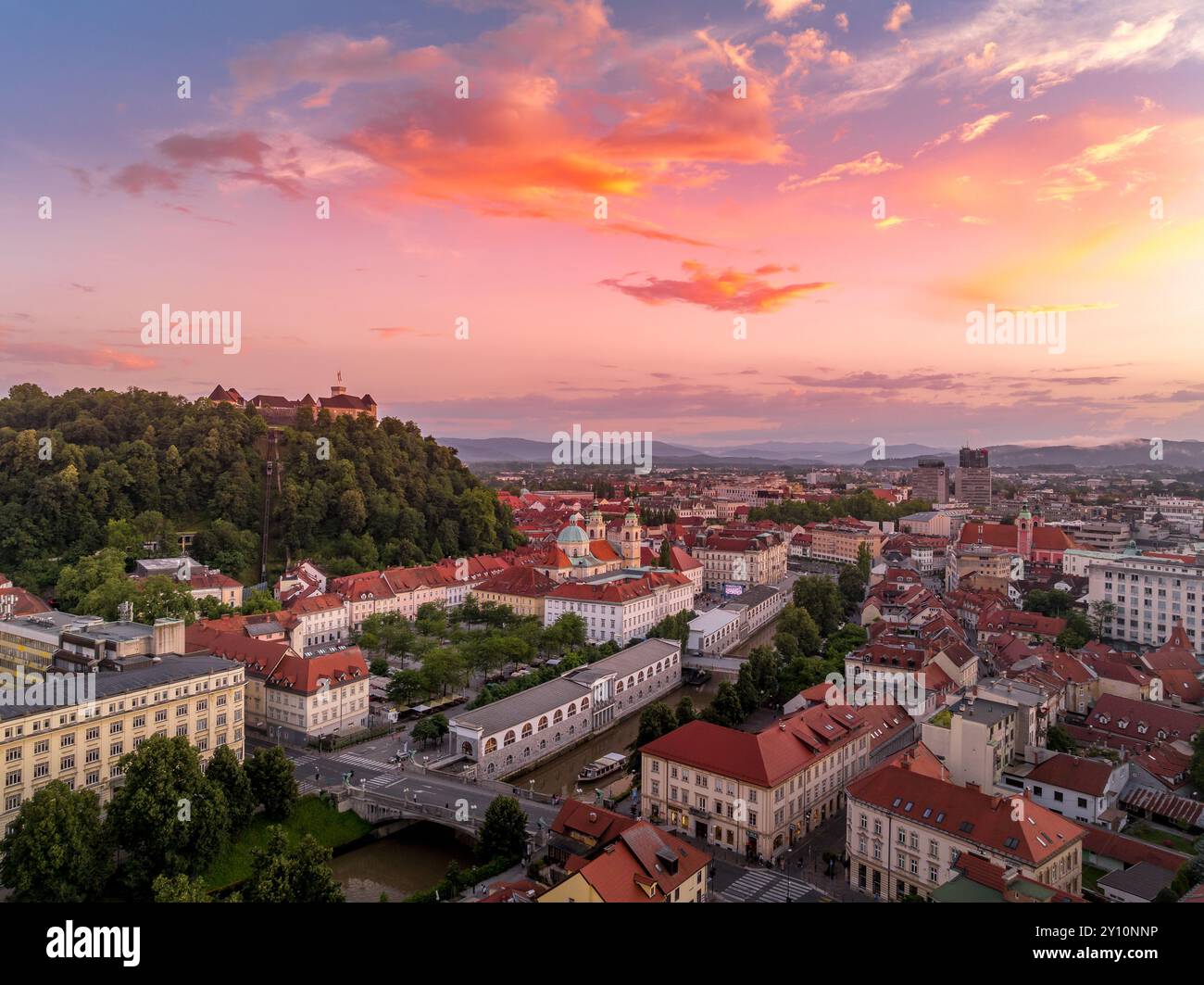 Blick aus der Vogelperspektive auf das Zentrum von Ljubljana Slowenien mit historischen Gebäuden, roten Dachhäusern auf dem Hügel, Kirchen in der slowenischen Hauptstadt Sonnenuntergang farbenfrohe s Stockfoto