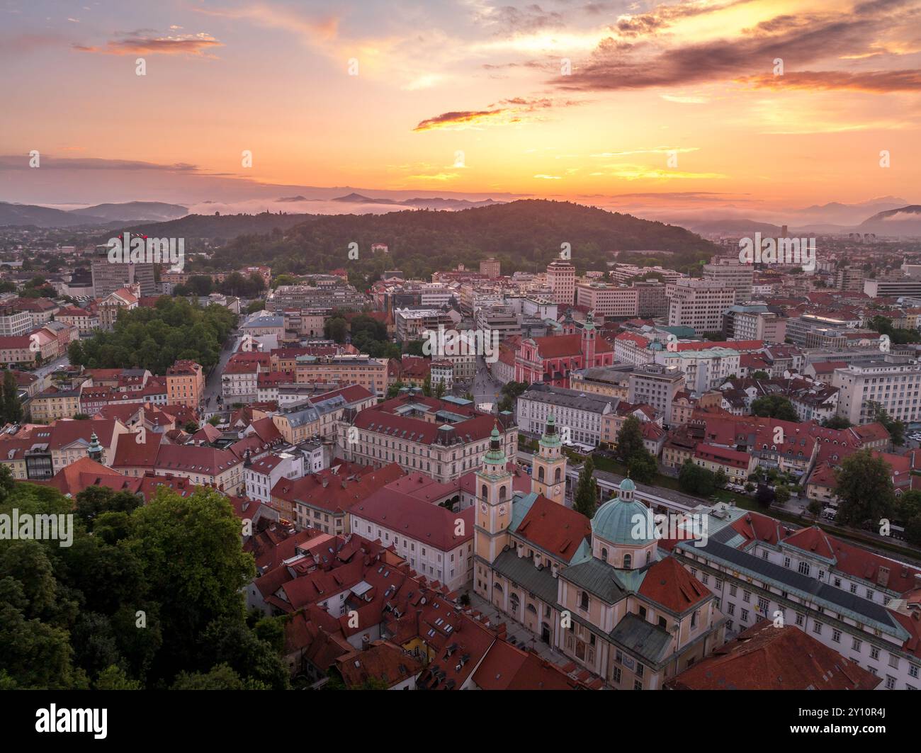 Blick aus der Vogelperspektive auf das Zentrum von Ljubljana Slowenien mit historischen Gebäuden, roten Dachhäusern auf dem Hügel, Kirchen in der slowenischen Hauptstadt Sonnenuntergang farbenfrohe s Stockfoto