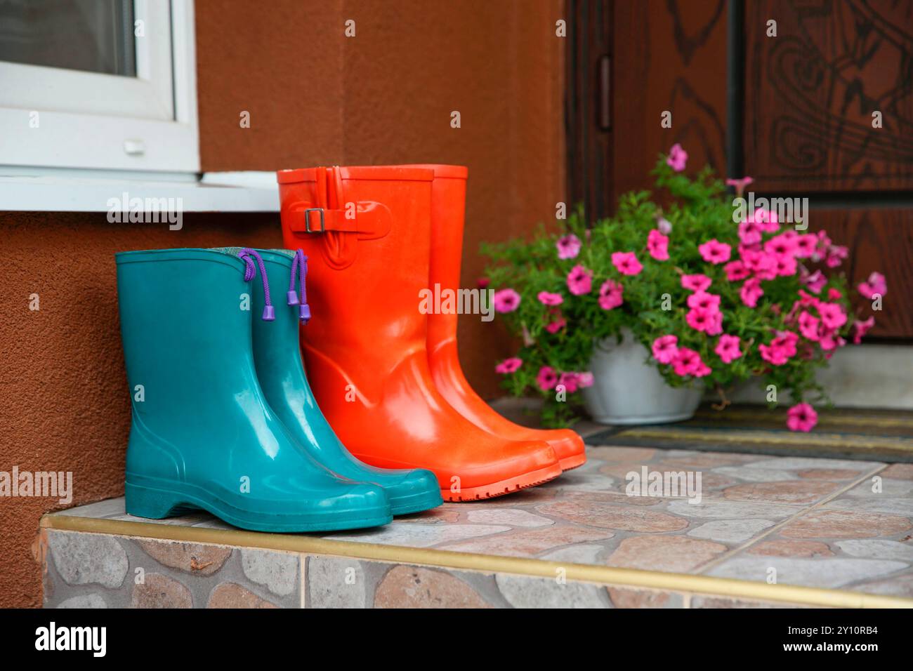 Zwei Paar Gummistiefel vor der Tür in der Nähe des Eingangs im Freien Stockfoto