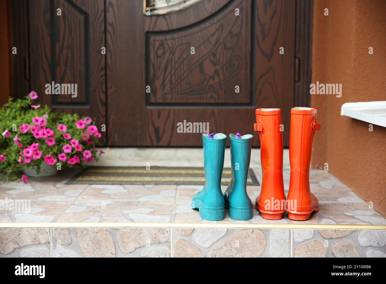 Zwei Paar Gummistiefel vor der Tür in der Nähe des Eingangs im Freien Stockfoto