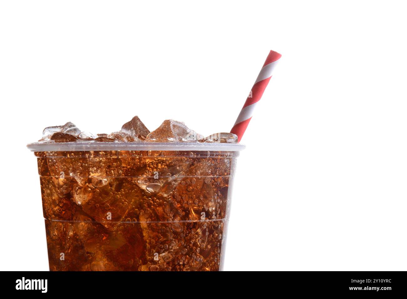 Nahaufnahme eines Plastikbechers gefüllt mit Eis und Cola. Nur die Hälfte des Bechers wird mit einem rot-weiß gestreiften Strohhalm auf weißem Hintergrund dargestellt. Stockfoto