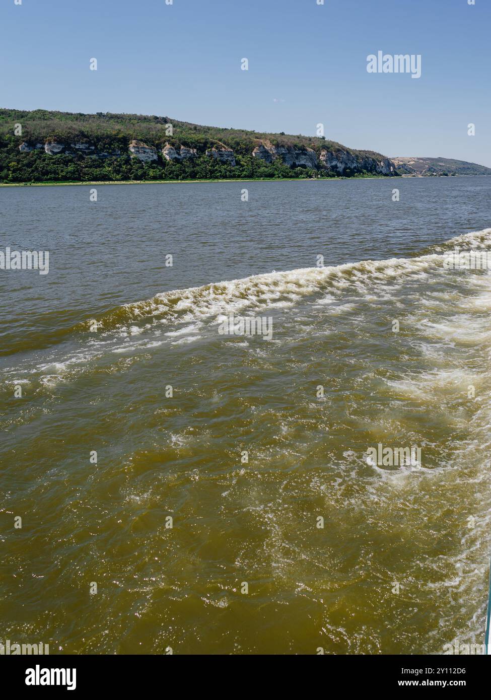 Panoramablick auf den Fluss mit felsiger Küste und bewaldeten Hügeln, Bootswache im Vordergrund Stockfoto