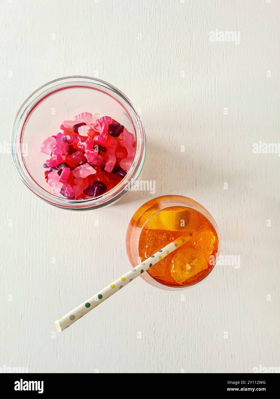 Ein alkoholfreies Getränk mit Stroh, Eiswürfeln und Orangenscheibe im Glas, Erfrischung im Sommer mit Gummibeeren als Snack Stockfoto