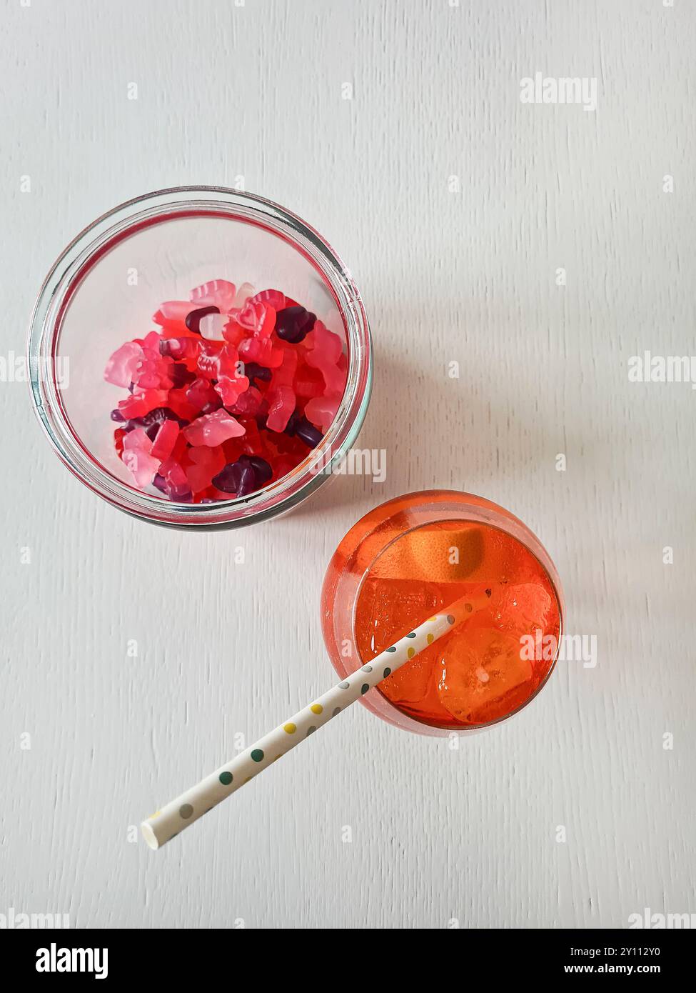 Ein alkoholfreies Getränk mit Stroh, Eiswürfeln und Orangenscheibe im Glas, Erfrischung im Sommer mit Gummibeeren als Snack Stockfoto