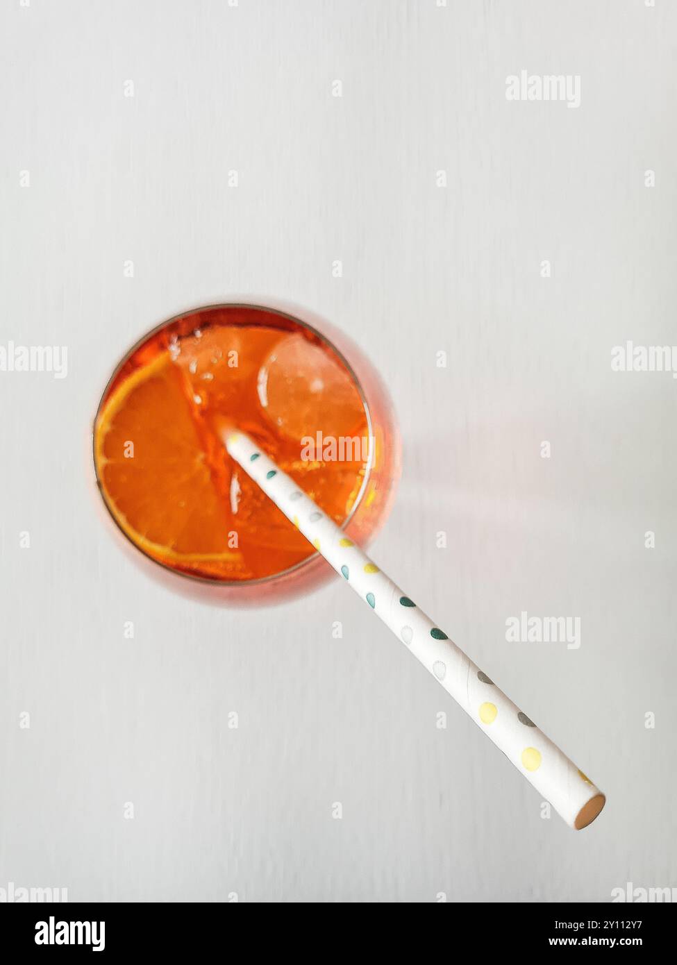 Ein alkoholfreies Getränk mit Stroh, Eiswürfeln und Orangenscheibe im Glas, Erfrischung im Sommer Stockfoto