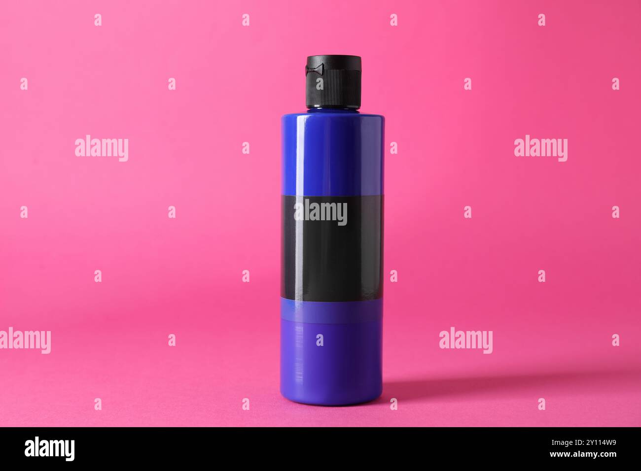 Blaue Acrylfarbe in der Flasche auf rosa Hintergrund Stockfoto