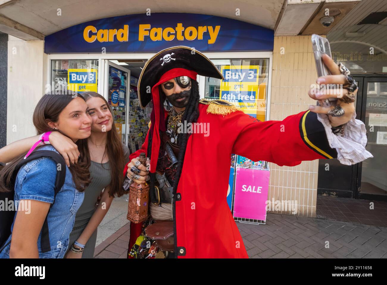 England, East Sussex, Hastings, das jährliche Pirate Day Festival, kostümierter Teilnehmer, der Selfie mit zwei jungen Touristen nimmt Stockfoto