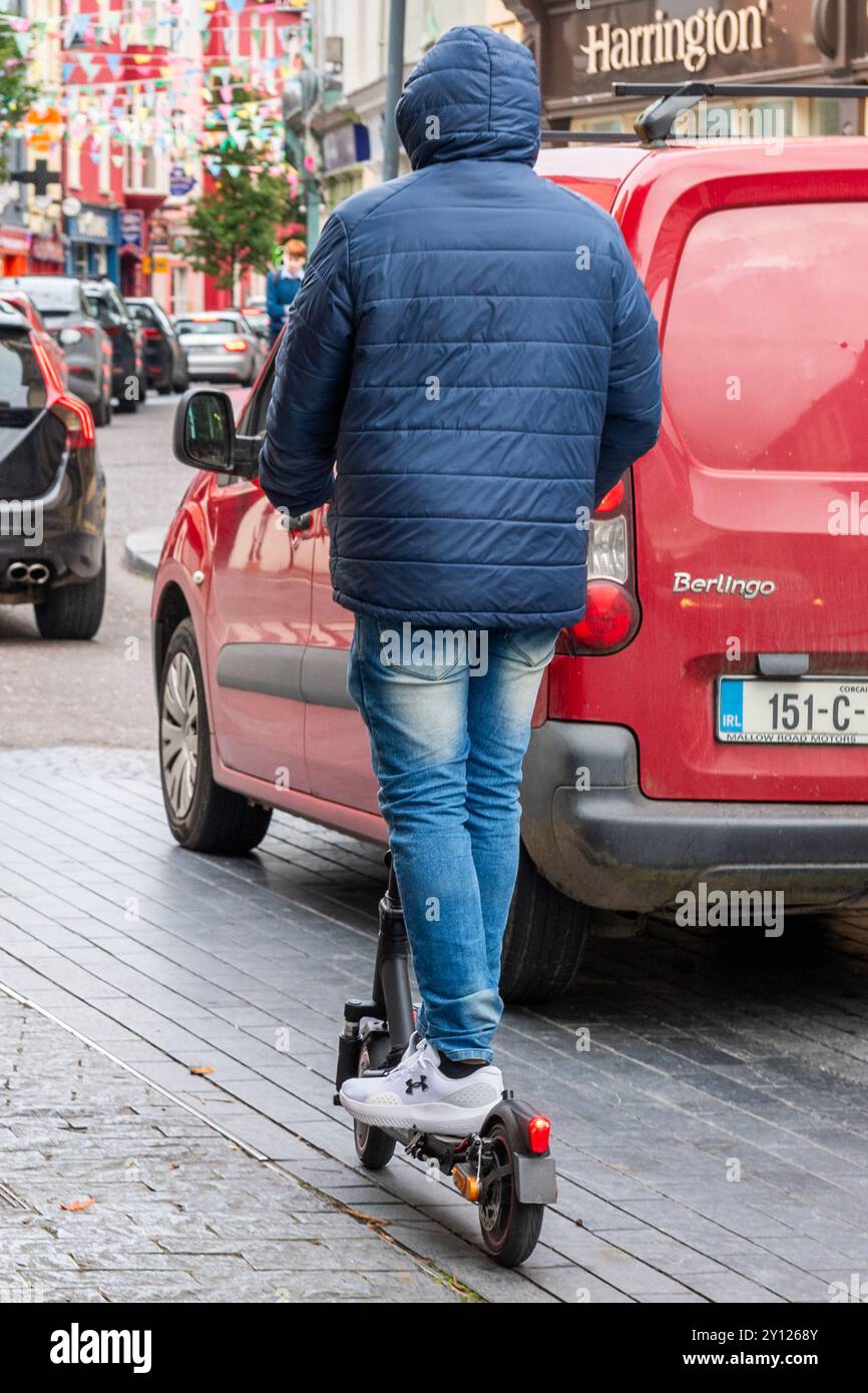 Mann auf einem E-Scooter, der durch Clonakilty, West Cork, Irland fährt. Stockfoto