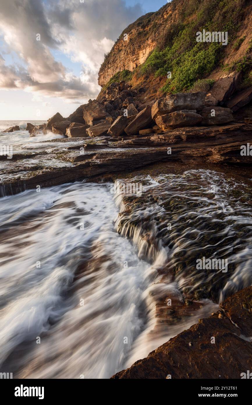 Dynamischer Sonnenuntergang über Felsen und Wellen am Little Beach an der Central Coast Australia in NSW Stockfoto