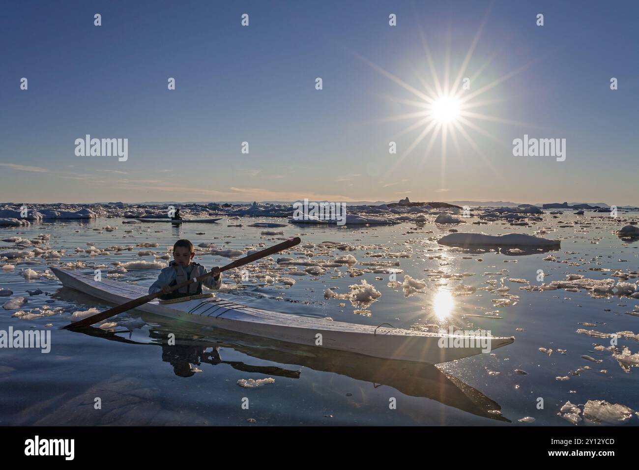 Kinder paddeln im Seekajak durch Eisschollen im Meer, Kajak, Hintergrundbeleuchtung, Sonnenstrahlen, Sommer, Ilulissat, Disko Bay, Grönland, Nordamerika Stockfoto