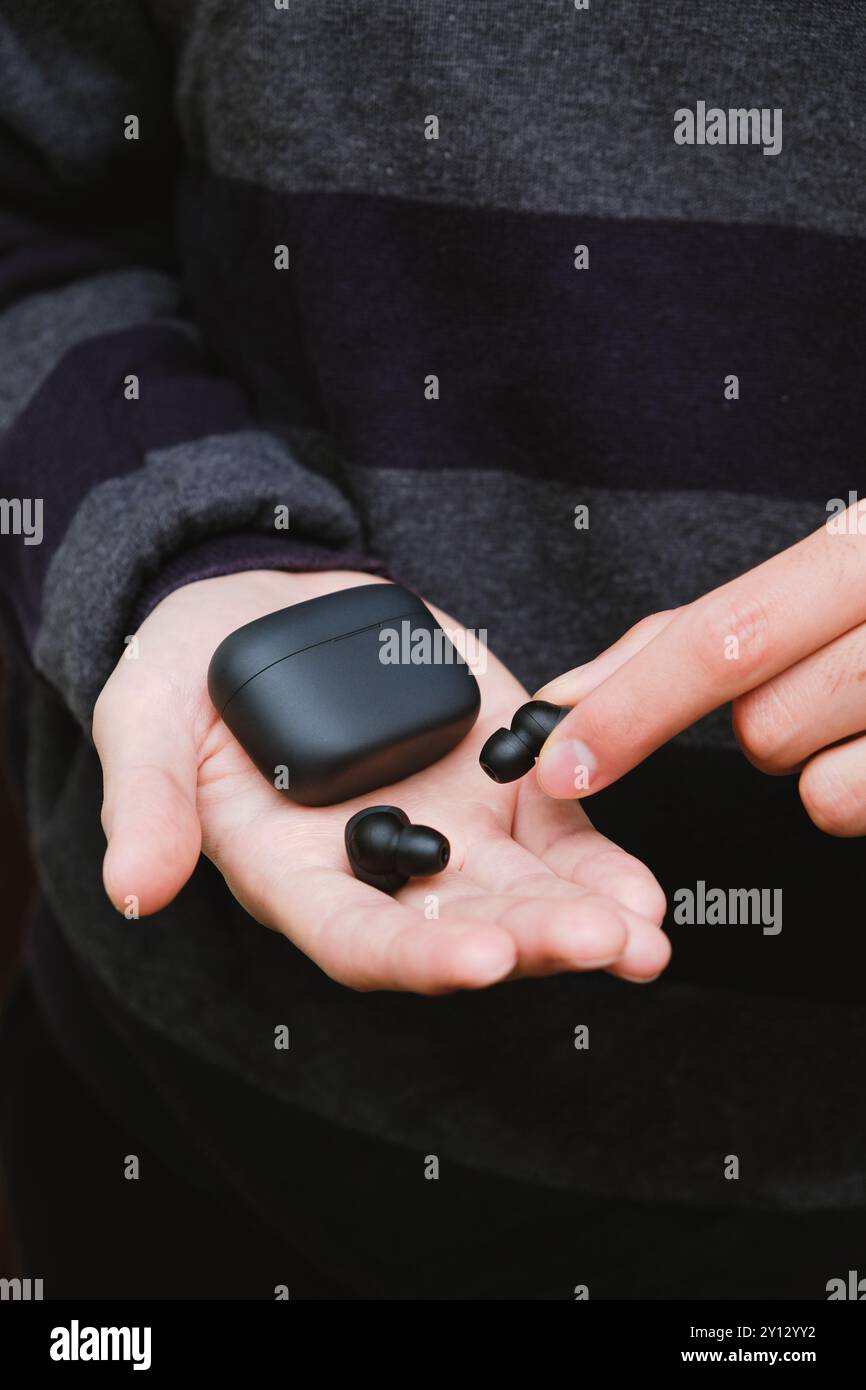 Mann mit schwarzen schnurlosen Ohrstöpseln und Einer Tasche. Moderner Lifestyle Stockfoto