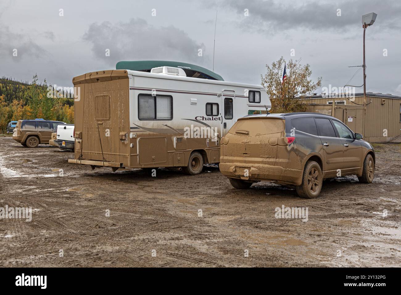 Schmutzige Autos und schlammiger Parkplatz vor dem Pub, Abenteuertourismus, Dalton Highway, Alaska, USA, Nordamerika Stockfoto