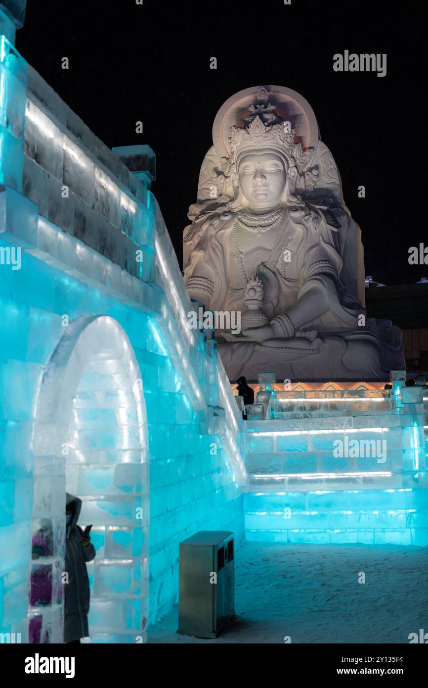 1. Januar 2022, HARBIN, CHINA. Vertikales Bild spektakulärer beleuchteter weißer Eisskulpturen in Harbin, China. Nachtbild mit Kopierraum für Tex Stockfoto