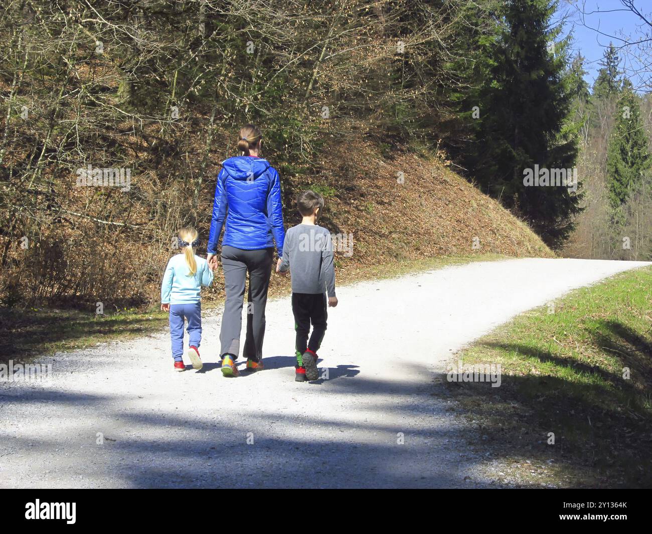 Mutter mit Sohn und Tochter wandern und Spaß haben und glücklich zusammen sein und Hände halten. Familienausflug in einen Wald im Frühling Stockfoto