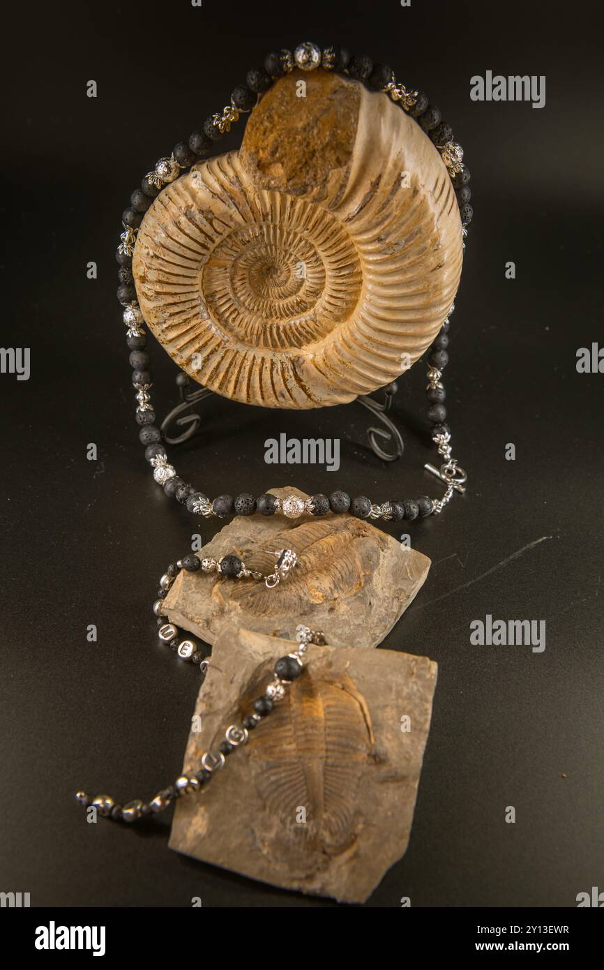 Handgefertigte Halskette und Ohrringe aus Silber und Vulkanstein auf Ammoniit und Trilobit auf Schwarz Stockfoto