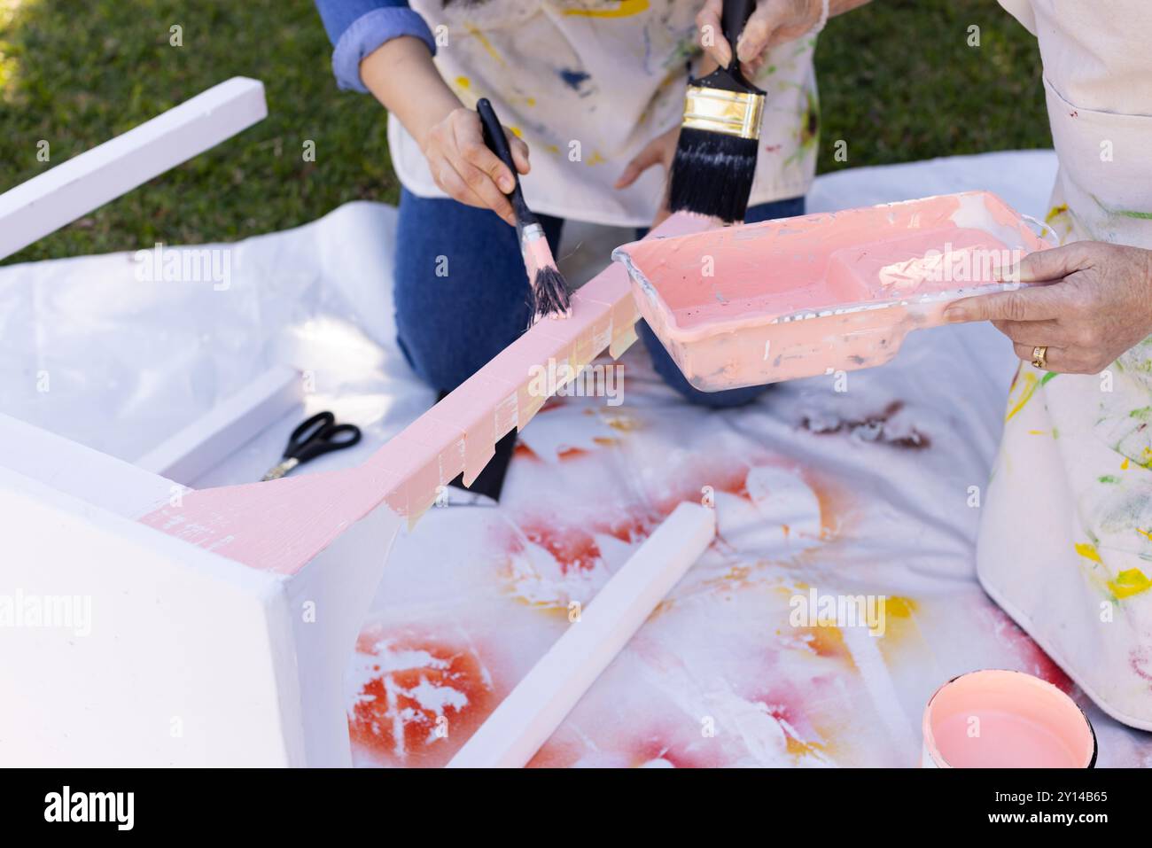 Möbel im Freien bemalt, zwei Personen mit Pinsel und rosa Farbe Stockfoto