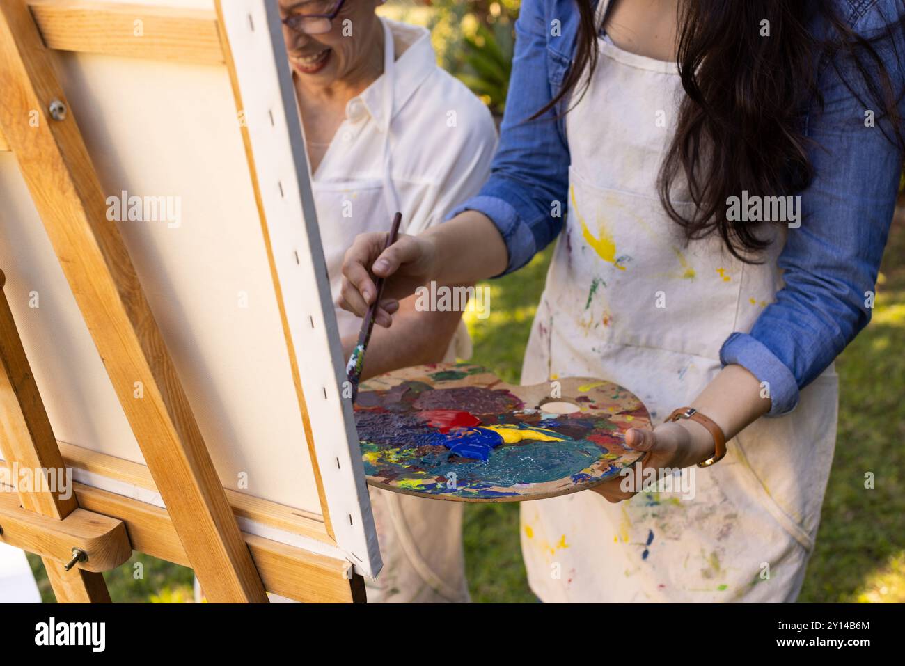 Malerei auf Leinwand, asiatische Enkelin und Großmutter, die Palette und Pinsel halten, schaffen Kunst Outd Stockfoto