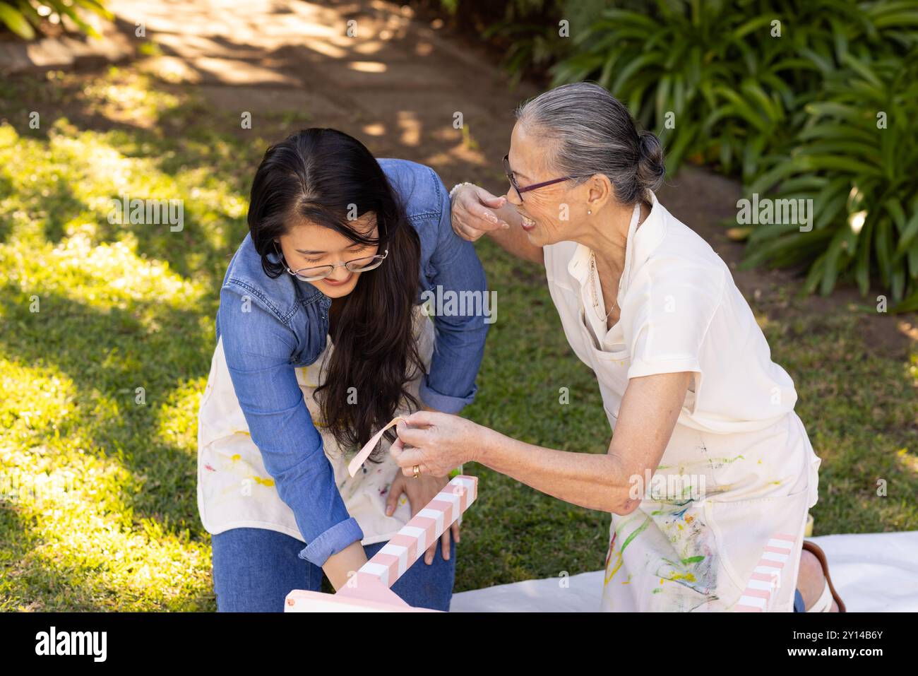 Gemälde von Holzmöbeln, asiatische Enkelin und Großmutter, die gemeinsam ein Outdoor-diy-Projekt genießen Stockfoto