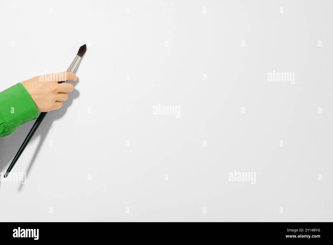 Weibliche Hand berührt weiße Leinwand mit Pinsel, Nahaufnahme. Künstlerhand mit einem Pinsel auf weißem Hintergrund Stockfoto