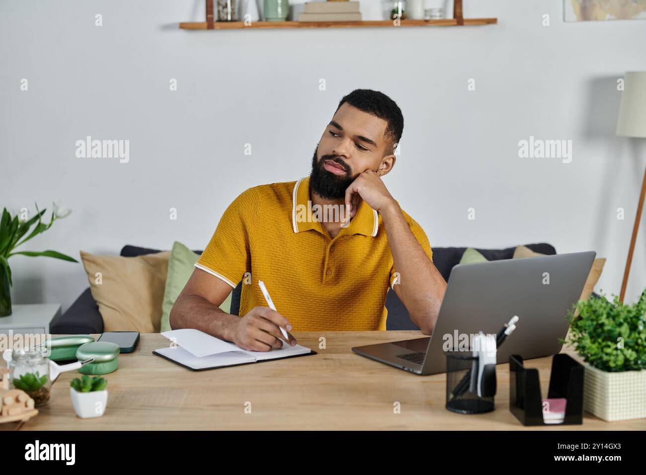 Ein Mann reflektiert, während er an einem ruhigen Nachmittag Ideen in sein Notizbuch schreibt. Stockfoto