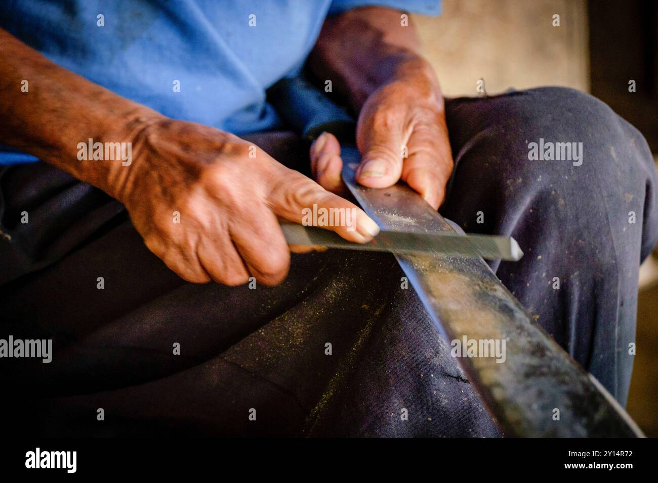 Alter Mann, der sein Messer schärft, kleiner Schatz, La Taña, Northern Transversal Strip, Quiché Department, Guatemala. Stockfoto