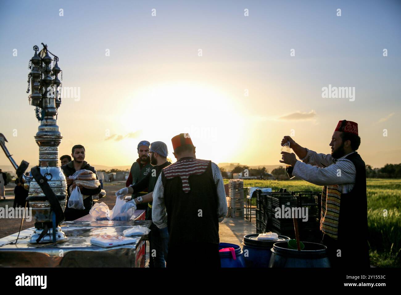 Idlib, Syrien. 19. April 2022. Verschiedene Organisationen verteilen iftar-Mahlzeiten sowie Tamarindensäfte und Lakritzgetränke während des Ramadan an die Bewohner von Vertreibungslagern in der Nähe von Sarmada, im Gouvernement Idlib. Die Schwierigkeiten der Vertriebenen in den Lagern in der oppositionellen Hochburg Idlib haben die Finanzkrise in der Türkei und den Fall der türkischen Lira sowie die anhaltende ukrainische Krise und die daraus resultierende Nahrungsmittelknappheit verschärft Stockfoto