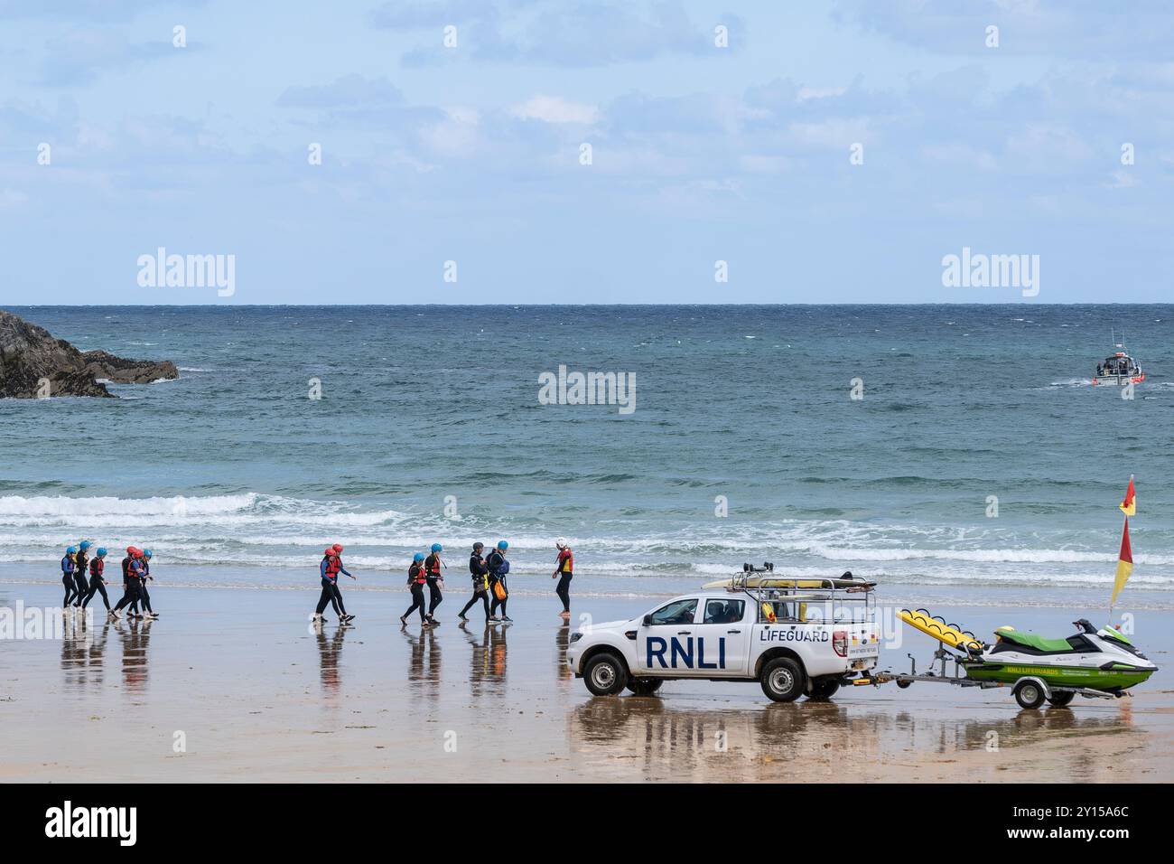 Coasteering Instruktoren führen eine große Gruppe von Menschen auf eine Küstenfahrt entlang des Towan Beach vorbei an einem RNLI Royal National Lifeboat Institutio Stockfoto