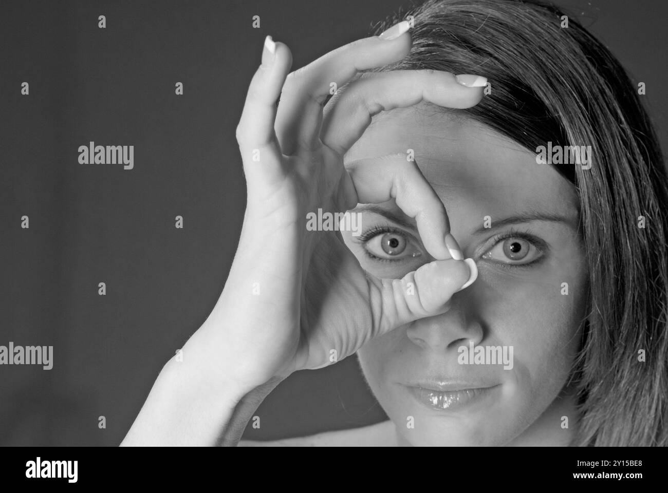 Nahaufnahme einer schönen kaukasischen Frau, 20 bis 25 Jahre, die durch ihre Finger schaut, USA. Stockfoto